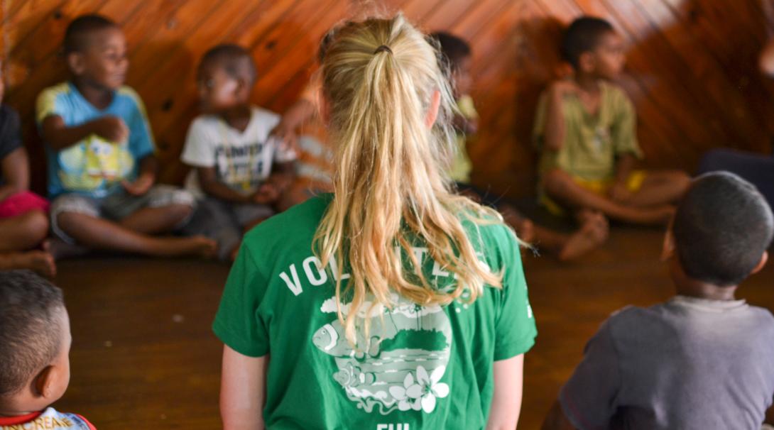 Durante su voluntariado social para jóvenes, una voluntaria ayuda en clases en Fiyi. Voluntaria internacional preparando su clase con niños en Fiyi.
